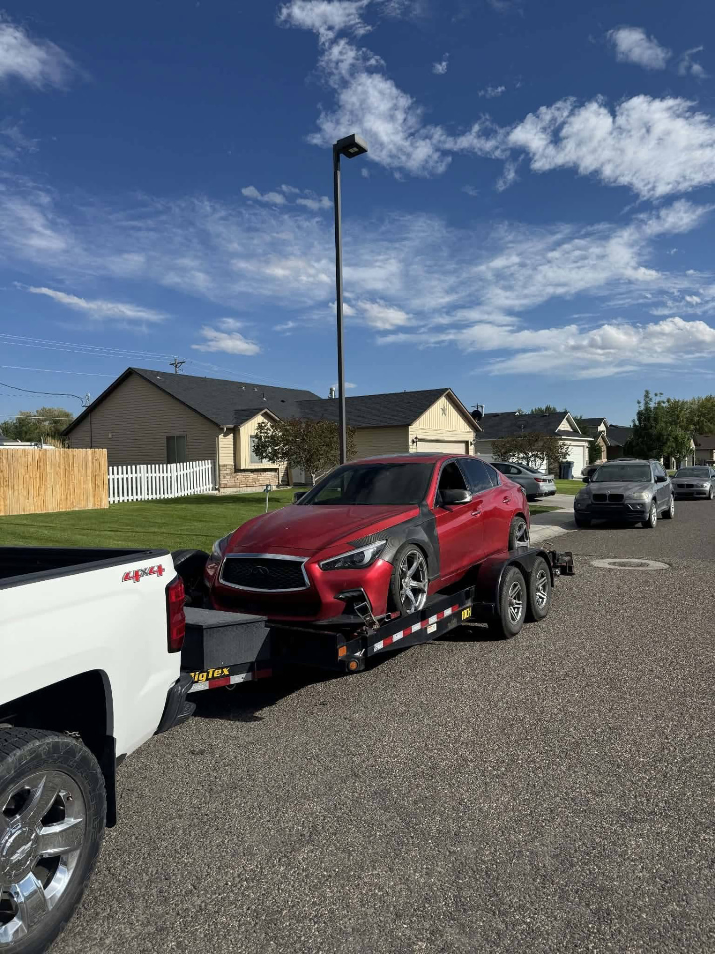 Red sedan being transported on a Gem State Haulers car trailer