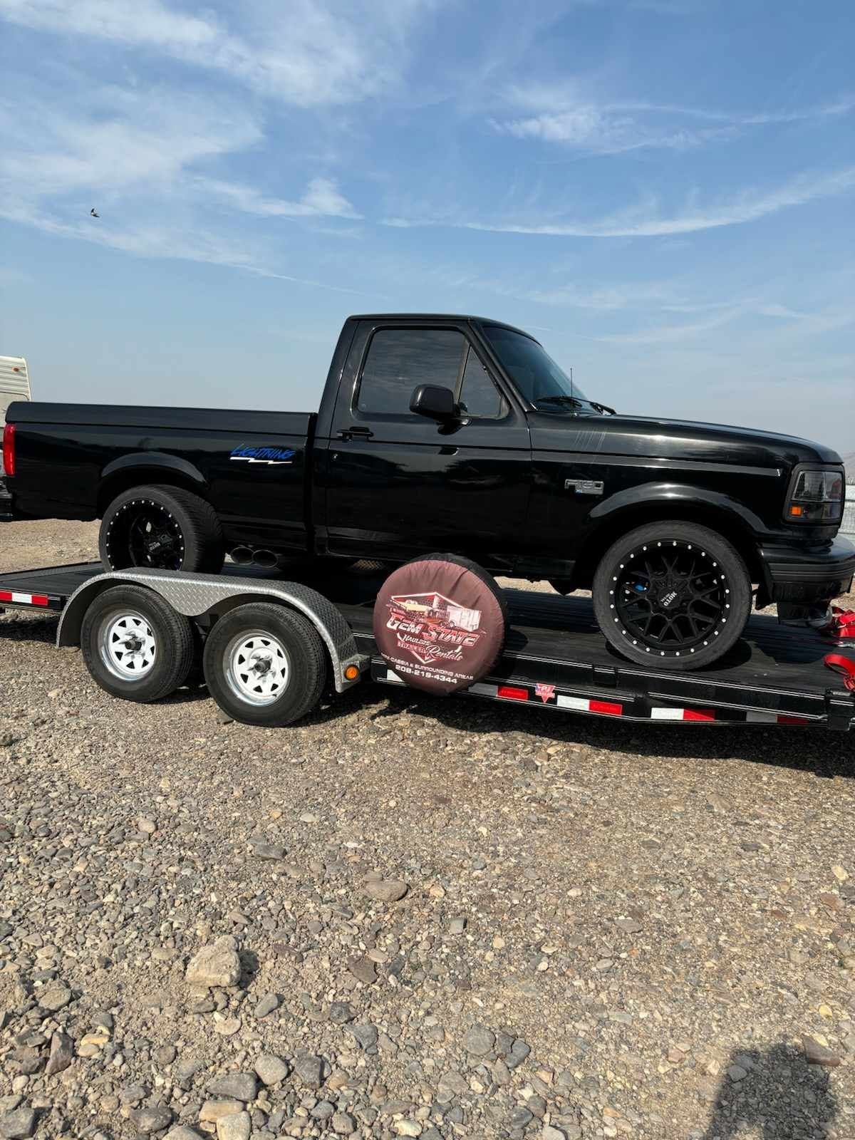 Black Ford pickup loaded on a Gem State Haulers car trailer